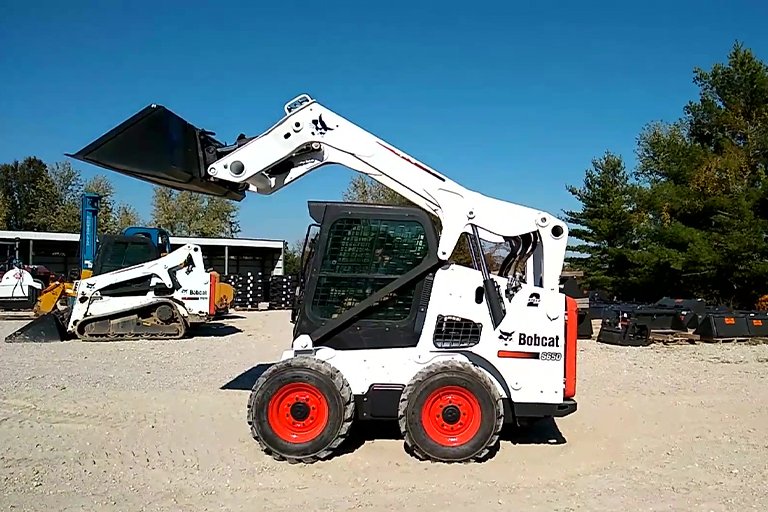 Bobcat skid steer with brush attachment sweeping construction site