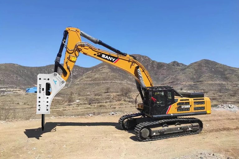 Excavator with hydraulic breaker attachment breaking concrete